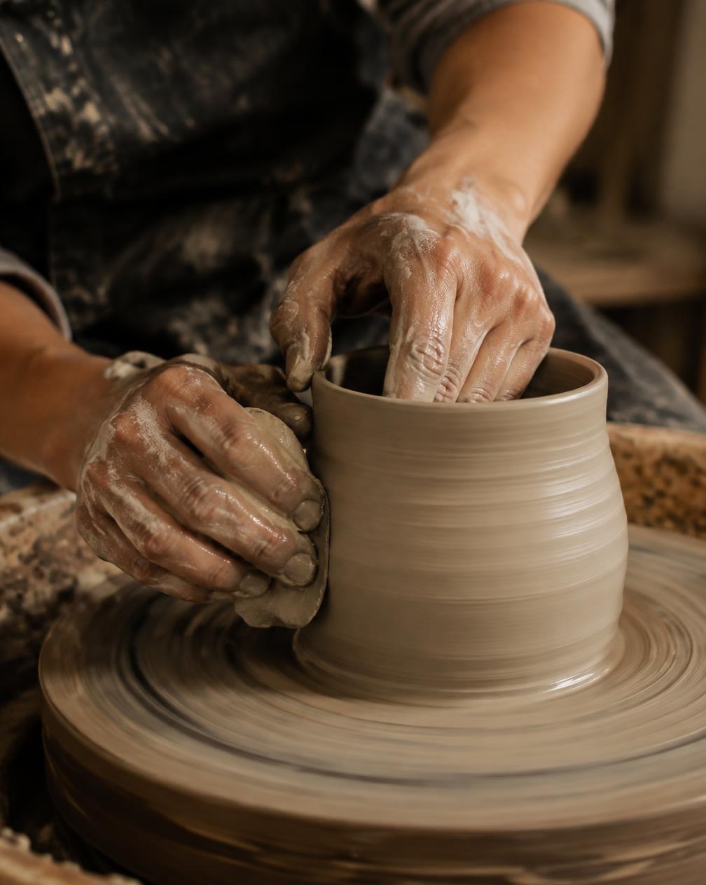 Hands shaping clay on a pottery wheel